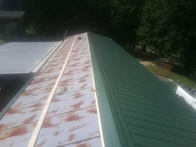 Old rusted panels beside newly installed green metal roofing — Wind Damage Roof Repair by Roofing Brothers in Roscoe